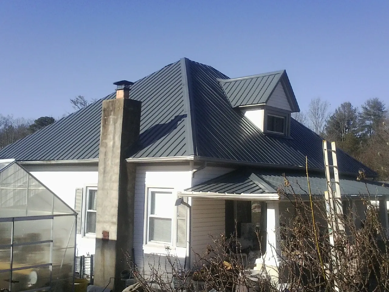 Dark blue standing seam metal roof on a white farmhouse with dormer — Slate & Tile Roof Repair by Roofing Brothers in Deptford