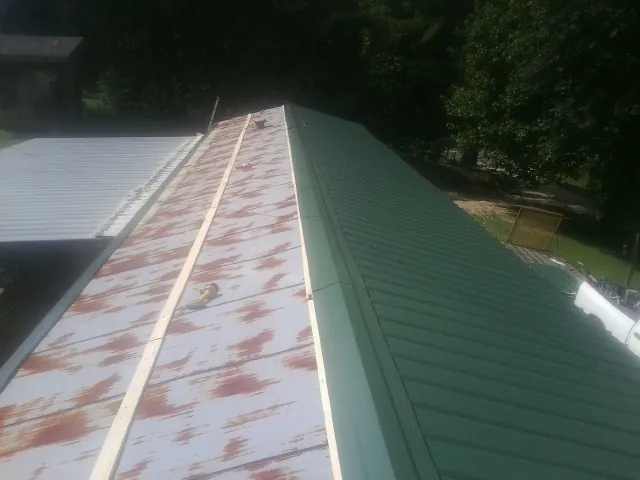 Old rusted panels beside newly installed green metal roofing — Wind Damage Roof Repair by Roofing Brothers in Deptford