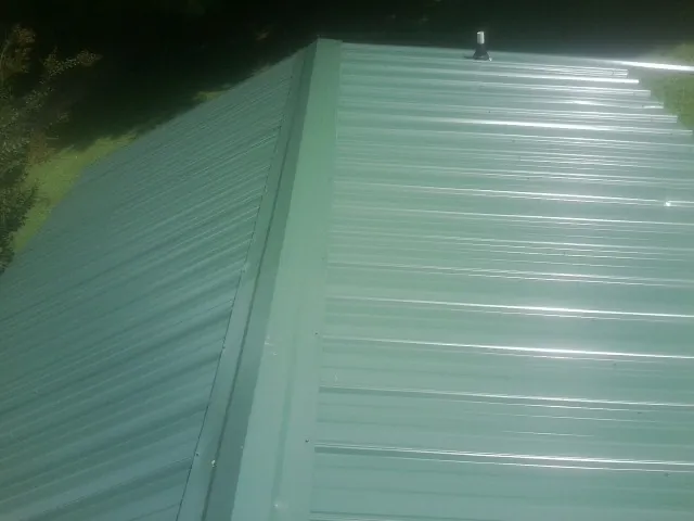 New green metal panels meeting at the ridge of a roof — Flat Roof Repair work by our crew in Deptford
