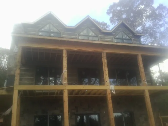 Dormers and porch framing on a large log home under construction — Roof Coating work by our crew in Deptford
