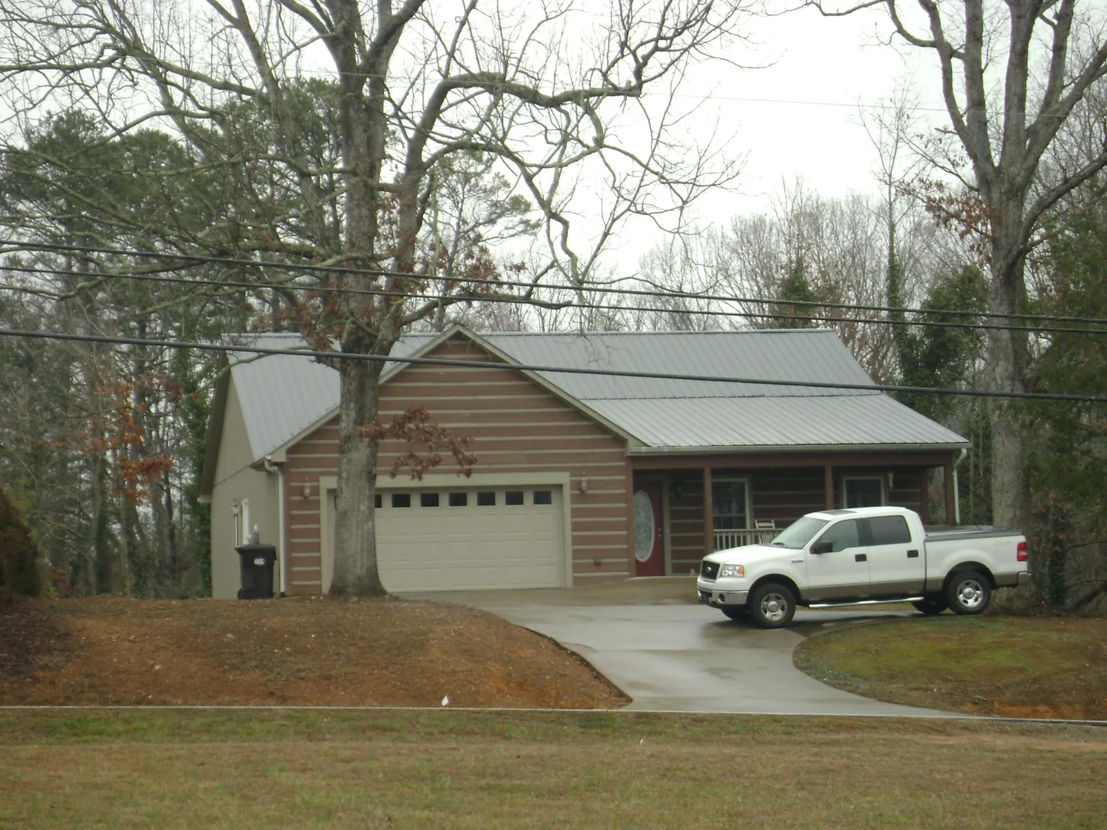 Gray metal roof on a log sided house with an attached two car garage in Deptford
