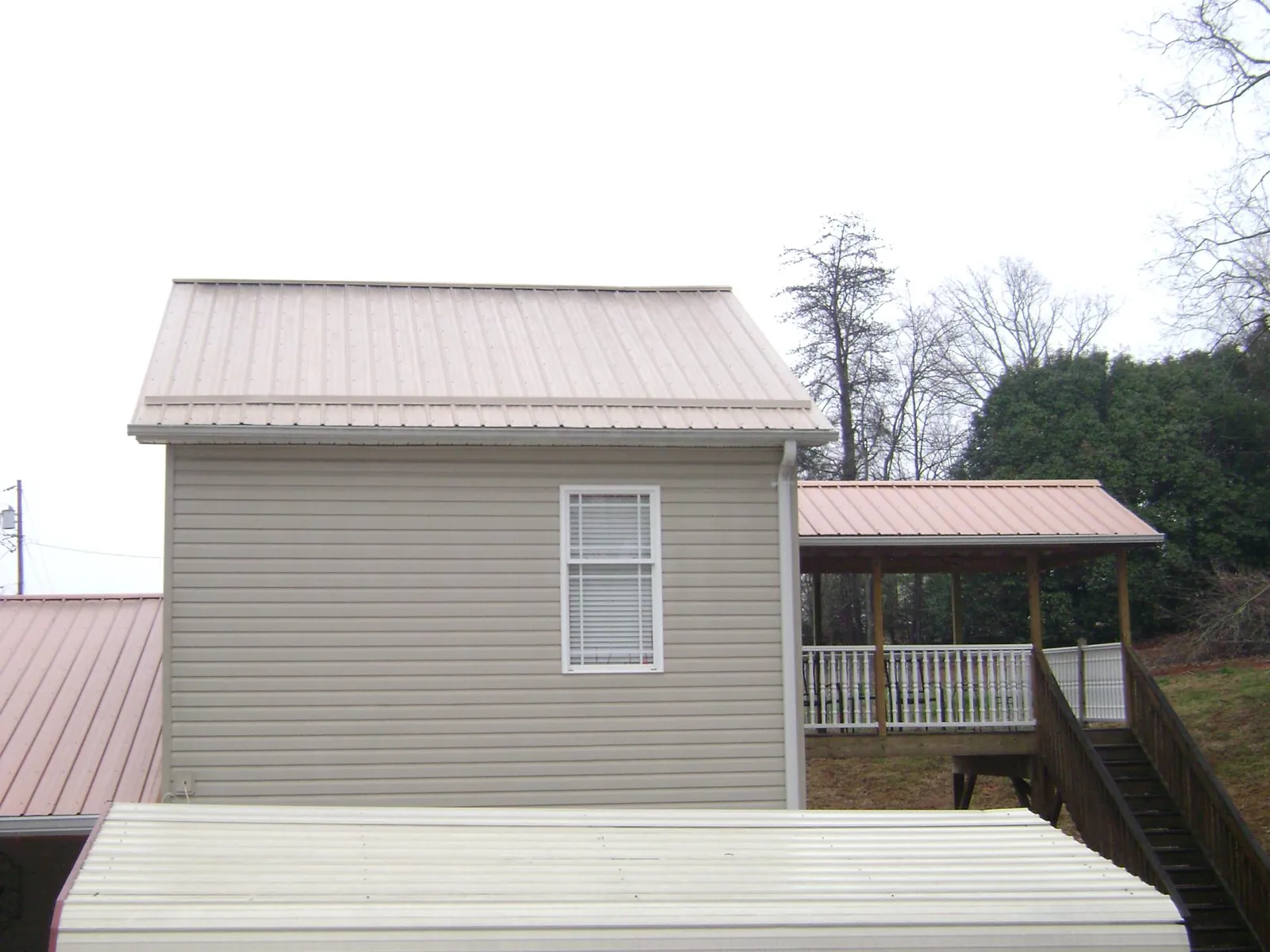 Tan metal roofs on a two story addition and attached porch, from a Roof Replacement job in Deptford