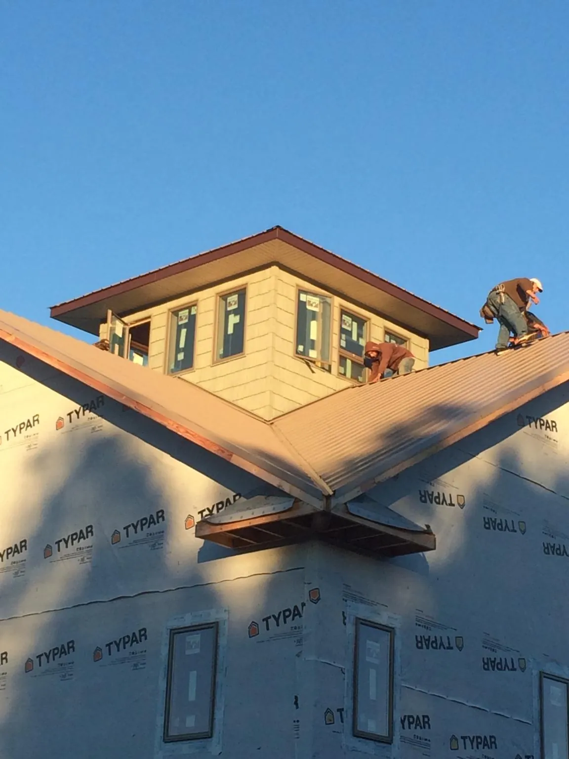 Roofers working around a rooftop cupola on a new metal roof at sunset — Roof Waterproofing in Deptford by Roofing Brothers
